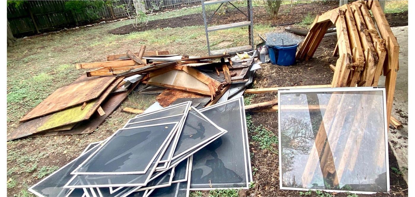 Before: a backyard pile of ripped-out window screens, plywood sheets and broken framing lumber left from a remodel.