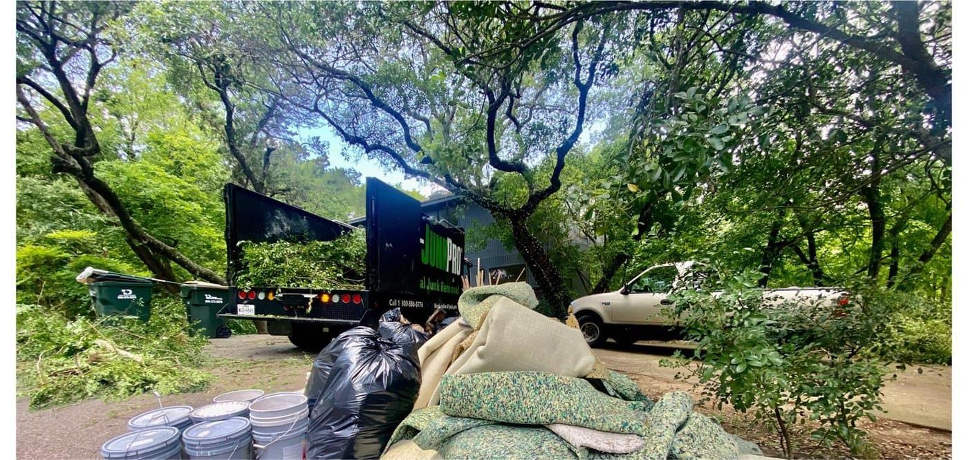 Before: a driveway beside a house piled with brush, branches and yard waste bags stacked against the garage.